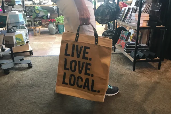 A woman is shopping and carries a bag that says live. Love. Local.